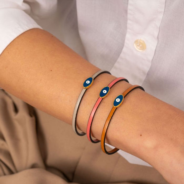 Χειροποίητο δερμάτινο βραχιόλι της Excite Fashion Jewellery, με λεπτό λουράκι και μεταλλικό επίχρυσο ματάκι με μπλέ σμάλτο. BM-1708-01-11-45