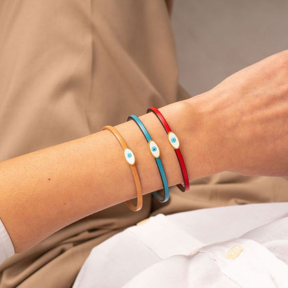 Χειροποίητο δερμάτινο βραχιόλι της Excite Fashion Jewellery, με λεπτό λουράκι και μεταλλικό επίχρυσο ματάκι με μπλέ σμάλτο. BM-1708-01-11-45